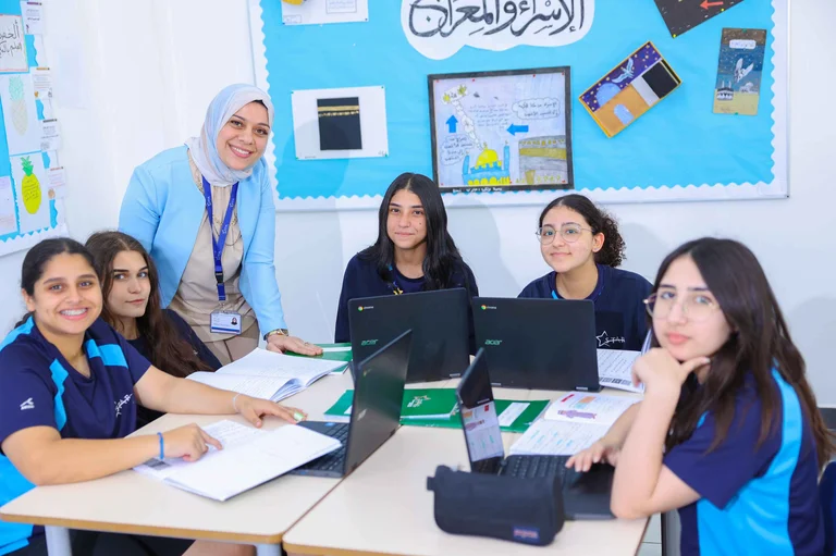 Teacher and students using laptops during a classroom lesson at Star International School Mirdif